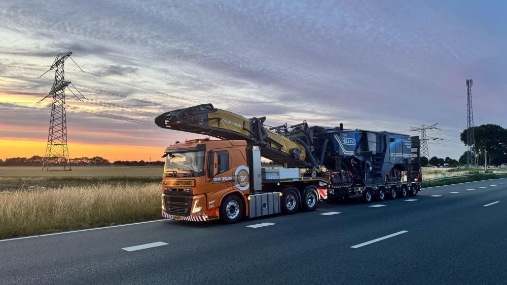 Waytrans heavy-haul prime mover transporting an oversized machine on a lowbed at dusk